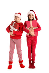 Little children in Santa hats with Christmas gifts on white background