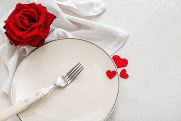 Table setting for Valentine's Day with red hearts and rose on white background
