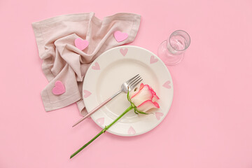 Table setting for Valentine's Day with hearts and rose on pink background