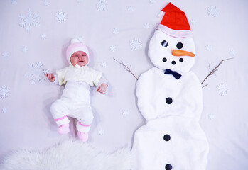 Newborn baby on a white background. Painting from white fabric. Snowman and baby. Christmas Holidays.