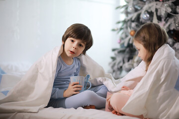 A family with children having fun on the bed under the covers during the Christmas holidays.