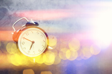 Background with a clock on the table and bokeh in pastel rainbow colors. Time for rest and travel.