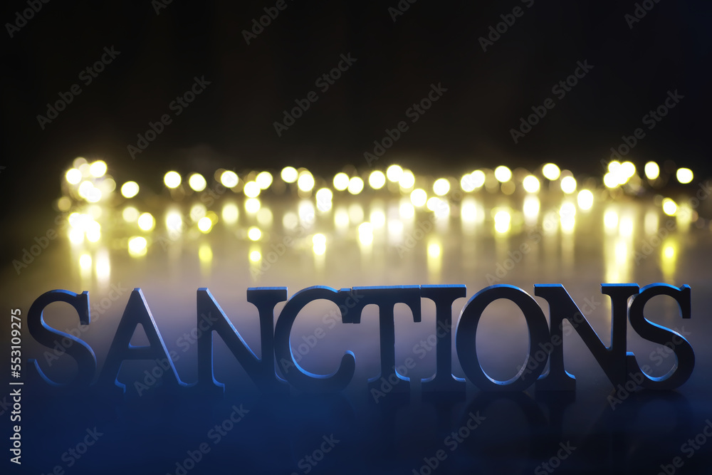 Wall mural word sanctions made of wooden block letters with dramatic lighting and smoke