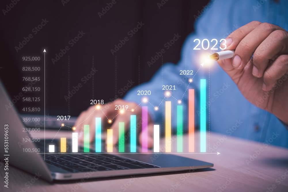 Aufkleber man hand holding a pen point on growth up business graph to year 2023