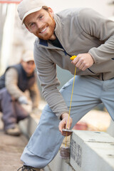 tradesman holding a plumb line beside concrete blocks
