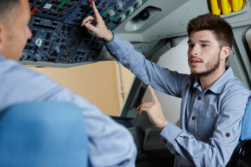 young man asking question during training session in aircraft cockpit