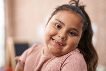 Plus size hispanic girl student using computer and headphones sitting on table at kindergarten