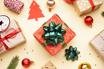 Fototapeta na wymiar Gift box with bow and Christmas balls on beige background, closeup