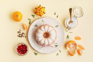 Composition with plate of tasty Christmas cake, tangerines and cranberry on yellow background