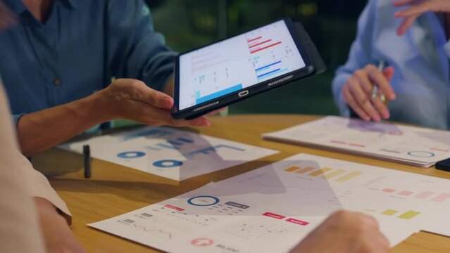 Close-up asia businesspeople meeting plan analysis statistics brainstorm and header of team hold tablet point graph chart and employee take note at home office night. Finance strategy success concept.