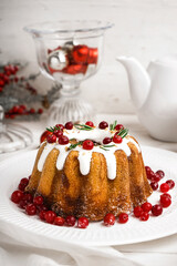 Plate of tasty Christmas cake with cranberry on light wooden table, closeup