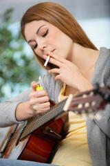 woman smokes while playing a guitar