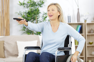 laughing mature woman in wheelchair watching movie on television