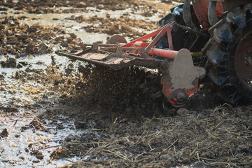 Agricultural tractors are plowing the soil in preparation for planting.