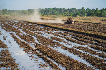 Agricultural tractors are plowing the soil in preparation for planting.