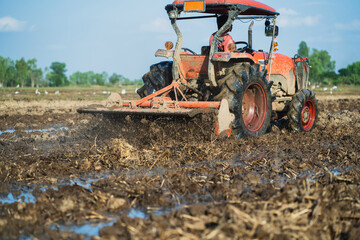 Agricultural tractors are plowing the soil in preparation for planting.
