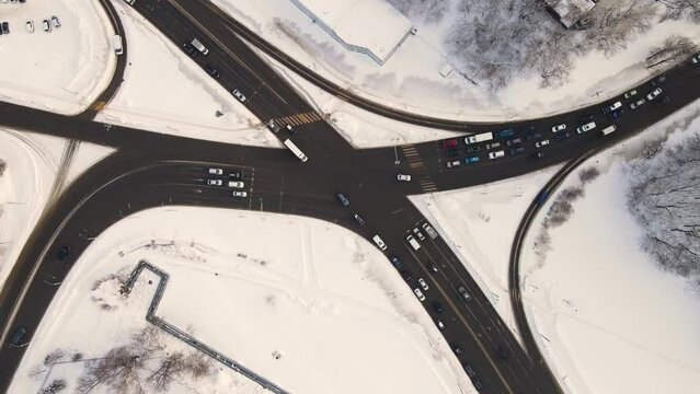 Bird's eye view in winter at the city crossroads with cars. Vehicles drive and stand at a traffic light. Regulated intersection, interchange. City of Vladimiro, Lybidskaya highway. UHD 4K.