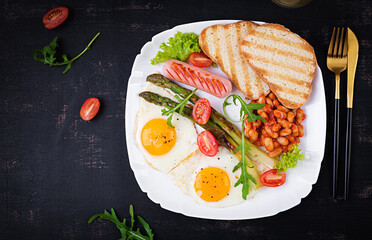 Keto breakfast. Breakfast. Fried eggs, bread toast, green asparagus, beans and sausage on white plate. Top view, flat lay
