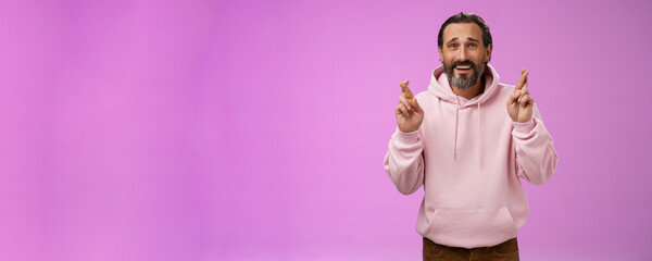 Hopeful lucky optimistic worried mature stylish bearded man grey hair in trendy hoodie cross...