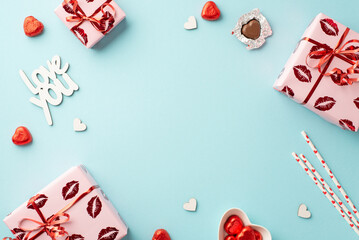 Valentine's Day concept. Top view photo of gift boxes in wrapping with kiss lips pattern heart shaped candies straws inscription love you on isolated light blue background with copyspace in the middle