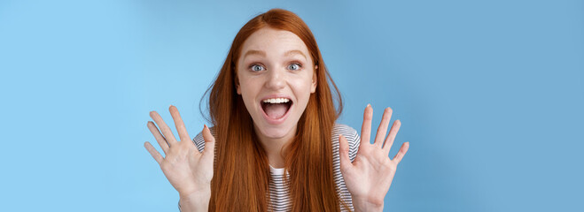 Naklejka na ściany i meble Excited charismatic happy lively redhead young funny woman smiling thrilled open mouth fascinated wide eyes surprised staring adore cool new product raise palms waving hello, show ten dozen
