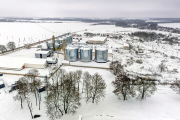 agro silos granary elevator in winter day in snowy field. Silos on agro-processing manufacturing...
