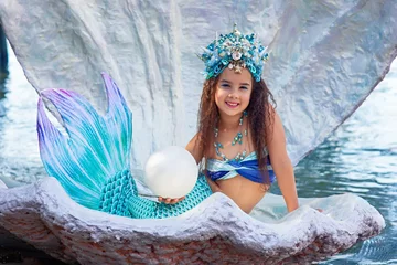 Foto op Plexiglas A beautiful happy little girl in a mermaid costume sits in a large sea shell © Natasha 