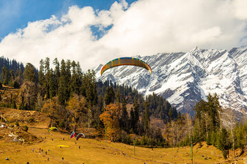 Paragliding in the blue sky with snow mountains of Manali in Himachal Pradesh. Panoramic views of...