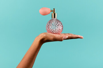 Black female hand showing classic perfume bottle