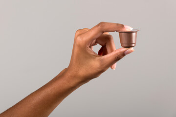 Black female hand showing coffee capsule