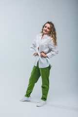 Young curly woman in a white cotton shirt and pants on a white background. Female mole