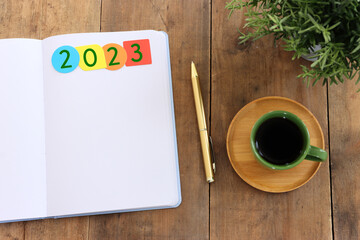 Business concept of top view 2023 goals with notebook, cup of coffee over wooden desk