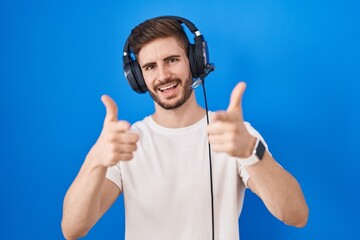 Hispanic man with beard listening to music wearing headphones pointing fingers to camera with happy and funny face. good energy and vibes.