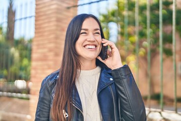 Young woman smiling confident talking on the smartphone at street