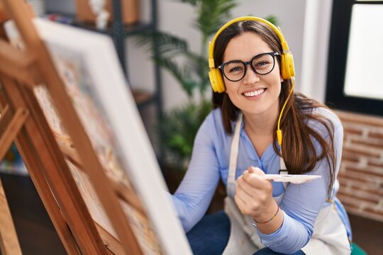 Young woman artist listening to music drawing at art studio
