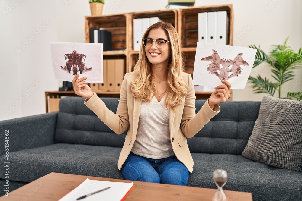 Sticker young blonde therapist woman holding rorschach test smiling with a happy and cool smile on face. sho