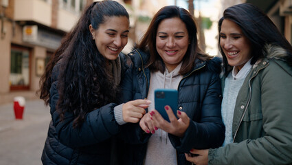 Mother and daugthers using smartphone standing together at street