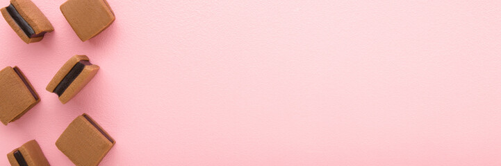 Brown jelly gummy candies with dark chocolate on light pink table background. Pastel color. Sweet...