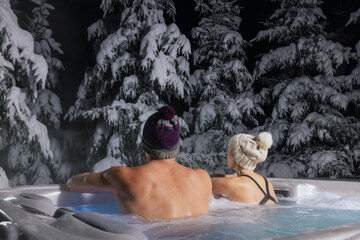 couple relaxing in outdoor hot tub and enjoying snowy forest. winter spa - obrazy, fototapety, plakaty