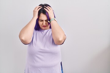 Plus size woman wit purple hair standing over isolated background suffering from headache desperate and stressed because pain and migraine. hands on head.