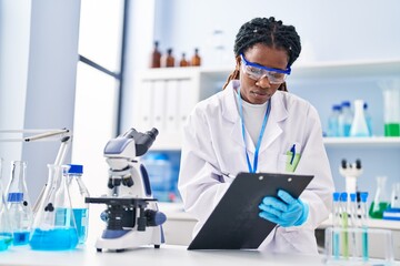 African american woman scientist writing report working at laboratory - obrazy, fototapety, plakaty