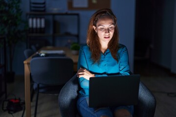 Brunette woman working at the office at night skeptic and nervous, disapproving expression on face...