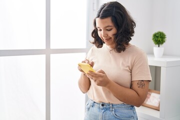 Young woman using smartphone standing at home