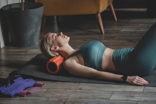 Woman with eyes closed lying on foam roller at home