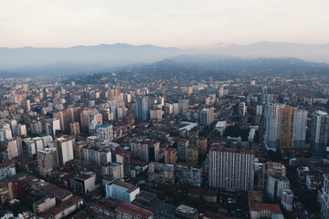 Fototapeta na wymiar Aerial view from drone of evening panorama Batumi city buildings with mountains at background in twilight.