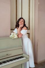 The bride leans on the piano and languidly looks into the lens