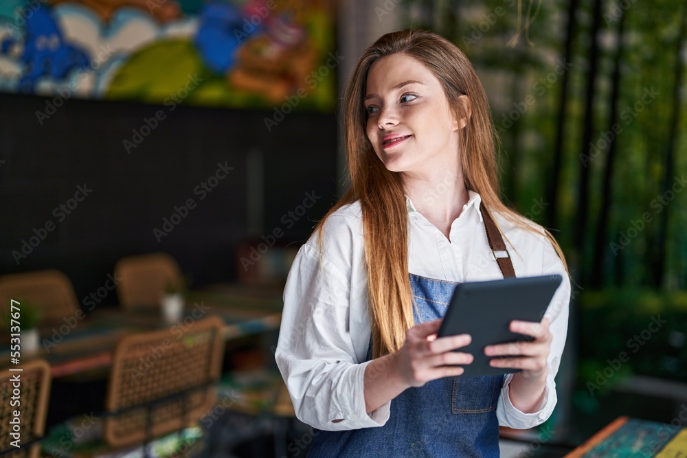 Sticker Young caucasian woman waitress smiling confident using touchpad at restaurant