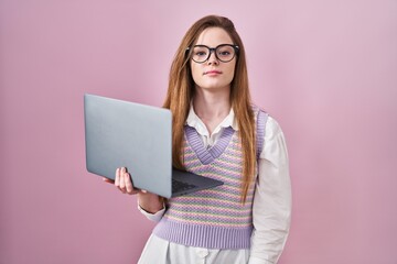 Young caucasian woman working using computer laptop relaxed with serious expression on face. simple...