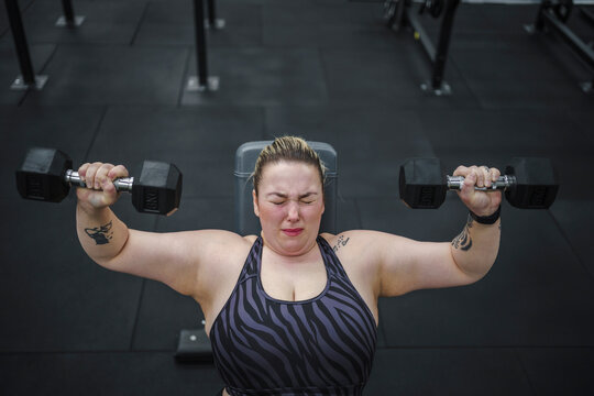 Dedicated Overweight Woman Doing Exercise With Dumbbells In Gym