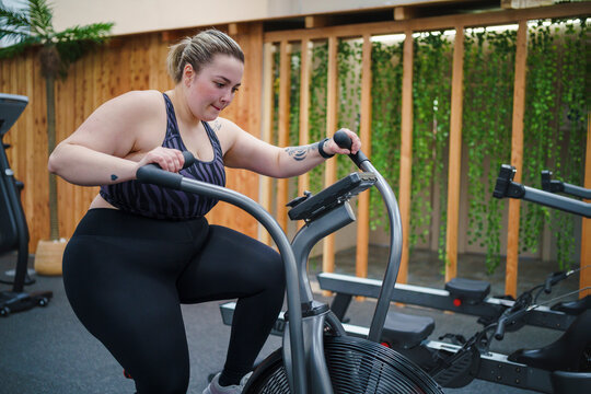 Overweight woman doing workout on cross trainer in gym